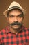 Indian tourist man with mustache wearing hat against brown background