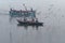 Indian tourists are surrounded by seagulls on boat on the river Ganges foggy morning. Varanasi