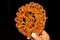 Indian traditional sweets jilapi or jalebi holding by hand to eat on black background