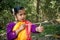 An Indian tribal little girl is playing with a bow and arrow in the forest alone