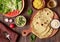 Indian vegetarian flat bread chapati with vegetables and hummus on a wooden table