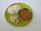 Indian vegetarian rice cakes breakfast known as idli or idly, served with sambar and Chatney in a green plate  in a white