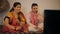 Indian village couple happily watching television together sitting on a woven cot