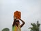 an indian village labour girl transporting bricks set on head at sky background isolated in India dec 2019