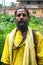 An Indian wanderer monk in a traditional yellow dress stands in a special posture