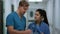 Indian woman doctor consulting man surgeon in hospital corridor close up.