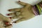 Indian woman hand wearing ethnic jewellery and applying nailpolish on white background