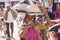 Indian woman with her cellphone shopping at vegetable market with a bag on her head