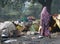 Indian woman in a purple saree passes by made-up tents in Bihar.