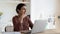 Indian woman sit at table with laptop thinking looks aside