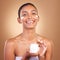 Indian woman, skincare cream and jar in hands for portrait, health and wellness by brown background. Young model, lotion