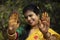 Indian woman with smiling face showing palms painted with mahendi or myrtle