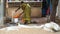 Indian woman washing orange plastic bowl.