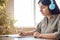 Indian woman wearing headphones writing in notebook listening course at home.