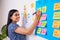 Indian woman writes ticket in backlog of colourful scrum board, KANBAN coding