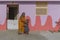 Indian woman in a yellow sari, with a child at the door