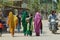 Indian women wearing colorful sarees walk by the street in Orchha, India.