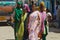 Indian women wearing colorful sarees walk by the street in Orchha, India.