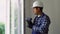 Indian worker with screwdriver installing and checking window in the house