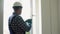 Indian workman in uniform installing or adjusting plastic windows in the living room at home