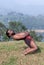 Indian yoga teacher doing backbend yoga exercise on green grass