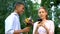 Indifferent teen girl ignoring boyfriend presenting flowers, chatting smartphone
