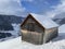 Indigenous alpine huts and wooden cattle stables on Swiss pastures covered with fresh white snow cover, Unterwasser