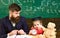 Individual lesson concept. Boy, child on calm face holds alarm clock while teacher talk to kid. Teacher with beard