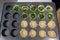 Individual quiches being made for breakfast, empty pastry shells in muffin tin ready to be filled, some with chopped onion