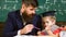 Individual schooling concept. Father with beard, teacher teaches son, little boy. Kid studies individually with teacher