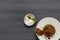 An individual spotted dick sponge cake, on a white plate with a spoon, and a small bowl of ice cream, on a dark grey wooden