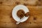 An individual spotted dick sponge cake, on a white plate with a spoon and sprinckled brown sugar, on a wooden surface