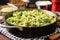 individual stirring broccoli rice in a skillet