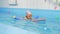 Individual swimming lesson with a personal trainer in an indoor pool. Happy preschool girl is learning to swim with pool