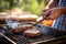 individual using a wide spatula flipping a burger on grill outdoors