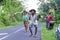 Indonesian old Man and old Woman carrying Palm tree leaves, logs and water in the middle of the road. Indonesia, July 2nd 2016