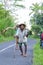 Indonesian old Man and old Woman carrying Palm tree leaves, logs and water in the middle of the road. Indonesia, July 2nd 2016