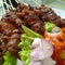 Indonesian pork satay with fresh lettuce, sliced tomatoes and shallots, one of the famous local dishes