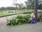 Indonesian woman playing cellphone and sitting on the floor alone in Bandung city park