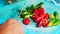 An Indonesian woman slicing chilli pepper with knife on cutting board.