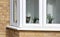 Indoor brown tabby cat with green eyes at the window looking directly at the camera seen from outside.