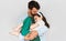 Indoor horizontal image of happy father embraces his cute daughter in his arms. Loving daddy and his little girl cuddling and