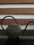 This is an indoor interior long tail jug. metal greenish tail jug