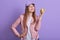 Indoor portrait of beautiful lovely teenager raising hand, holding apple, eating vitamins, being vegetarian, leading healthy