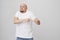 Indoor portrait of funny excited bald caucasian guy making dance move as if celebrating something, being in great mood