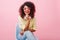 Indoor portrait of glamorous black woman with inspired smile sitting in chair and gently touching her chin. Laughing