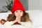 An indoor portrait of a little girl in a knitted warm red cap holding Christmas decorations - a photo representing a concept
