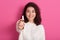 Indoor portrait of positive charismatic cute female smiling sincerely, showing her choice, holding tampon at foreground, being in