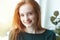 Indoor portrait of pretty smiling red haired young girl, sunny morning light