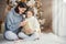 Indoor shot of adorable girl and her mother sit crossed legs, open wrapped present box, have intrigue what is there, sit against a